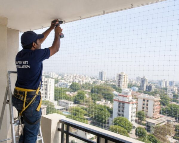 Technician installing balcony safety net in a high-rise apartment building for child safety, pet protection, and pigeon prevention in Bangalore